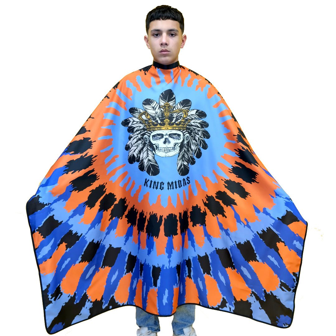 A person modeling a barber cape/ cape for barbers, with a geometric and tribal design in blue and orange shades, featuring a  of a skull with a headdress.