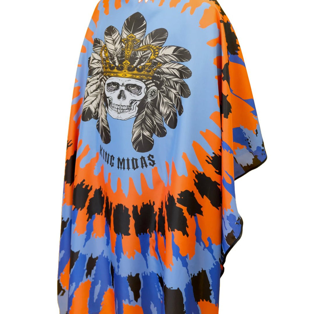 A person modeling a barber cape/ cape for barbers, with a geometric and tribal design in blue and orange shades, featuring a  of a skull with a headdress.