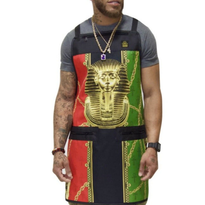 A person wearing a colorful barber apron with a pharaoh design, featuring gold, red, and green colors.