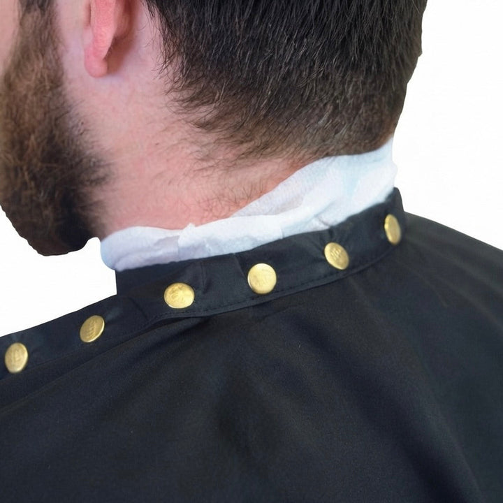 Close-up back view of a person wearing a custom barber cape with gold-tone snap buttons and a white neck collar.