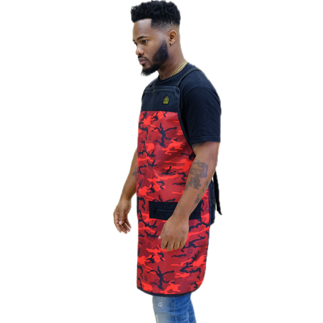 A man wearing a red and black camouflage apron over a black t-shirt and blue jeans, shown from a side profile against a plain white background.