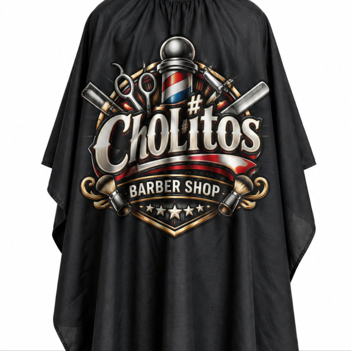 A black barber cape with a large barbershop logo on the front featuring the text 'ChoLitos BARBER SHOP' and barbershop-themed tools and colors, shown against a plain white background.