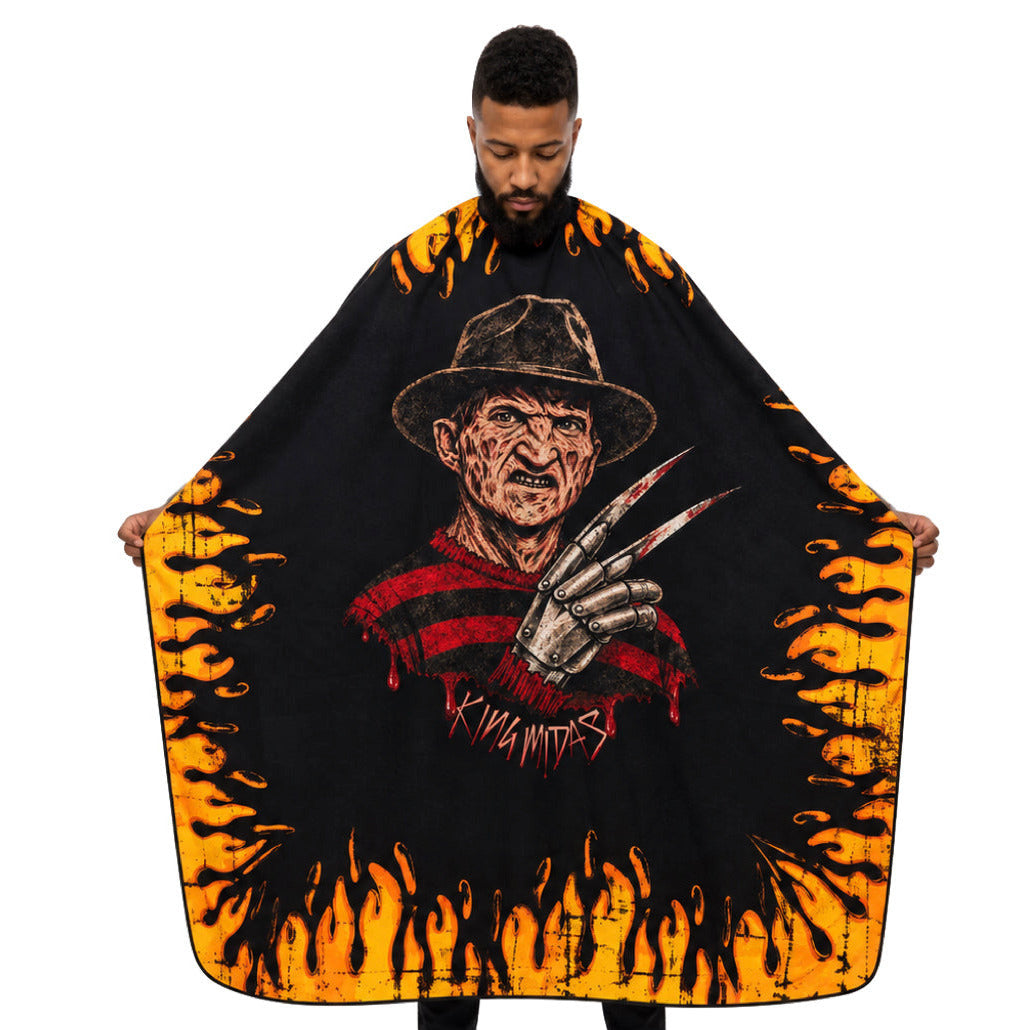 A man modeling a large freddy kruegar barber cape  featuring a horror character graphic in the center and bright orange flames around the edges, against a plain white background