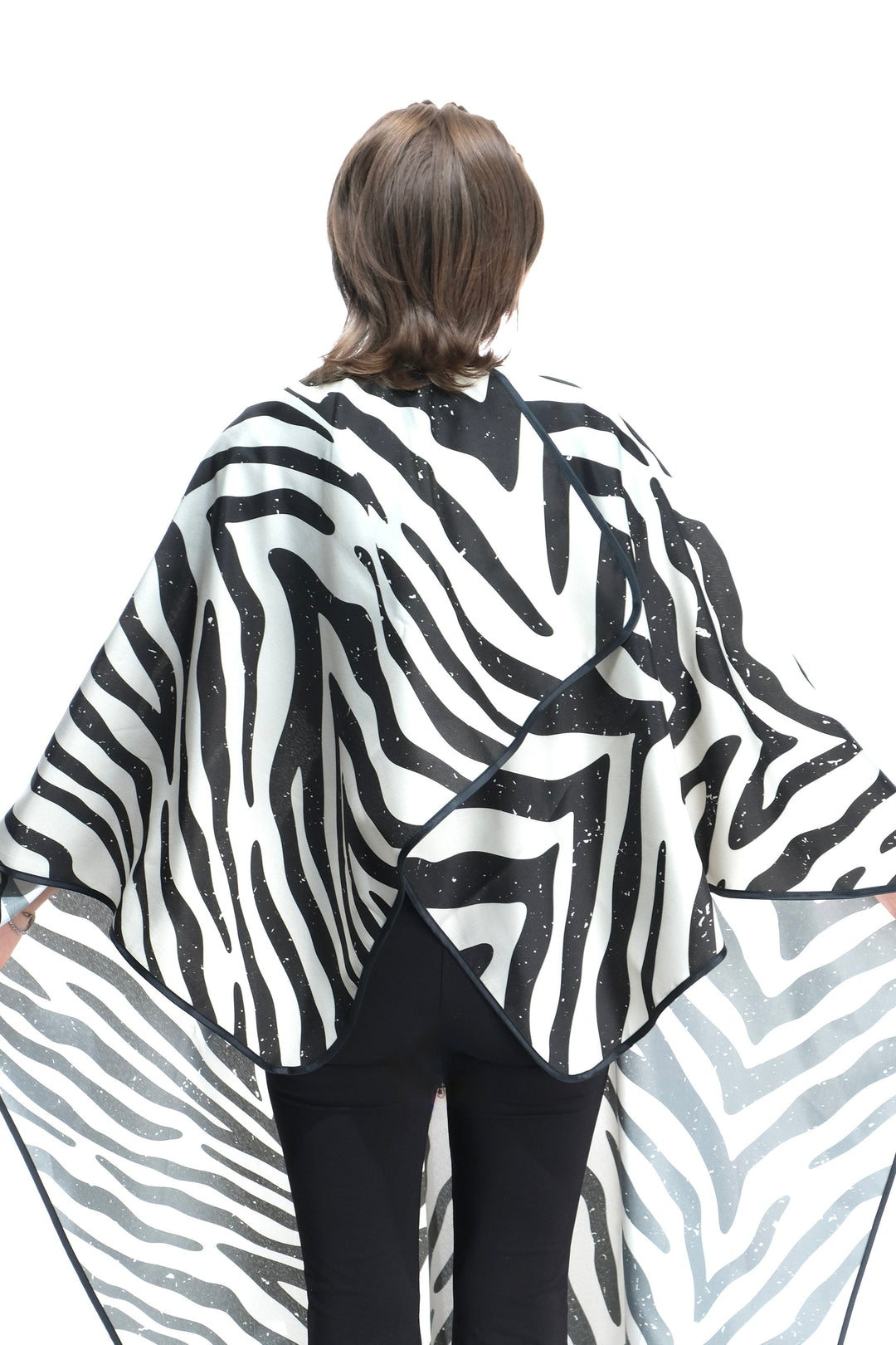 Person wearing a zebra print salon cape on a white background