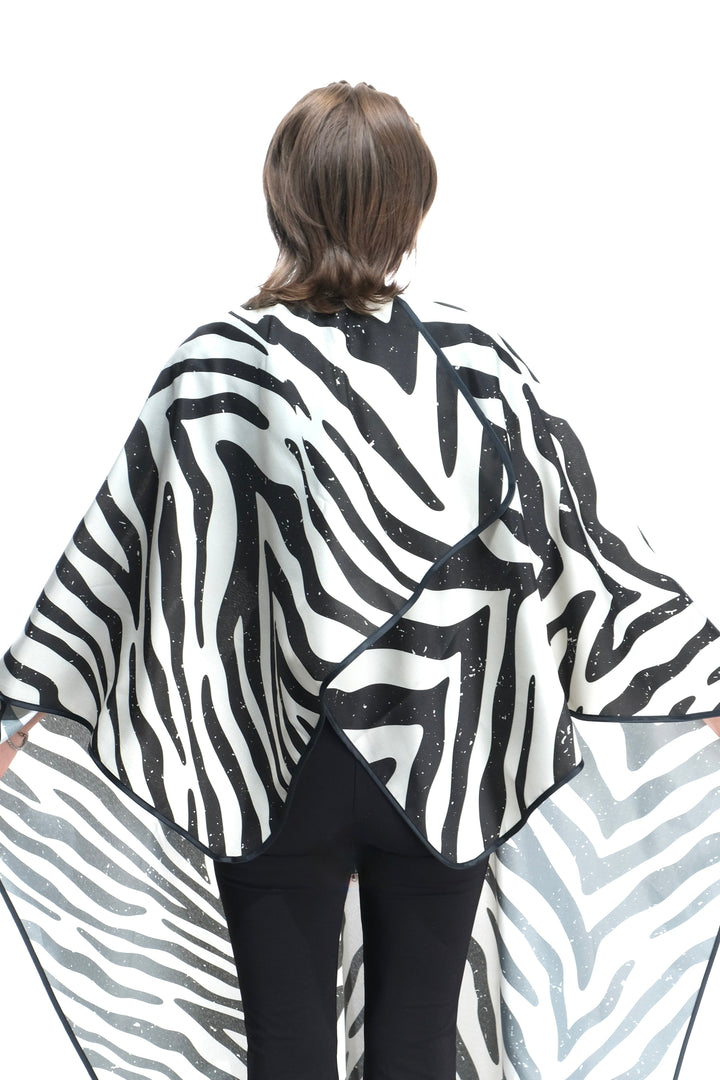 Person wearing a zebra print salon cape on a white background