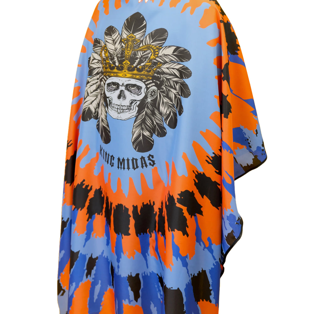 A person modeling a barber cape/ cape for barbers, with a geometric and tribal design in blue and orange shades, featuring a  of a skull with a headdress.