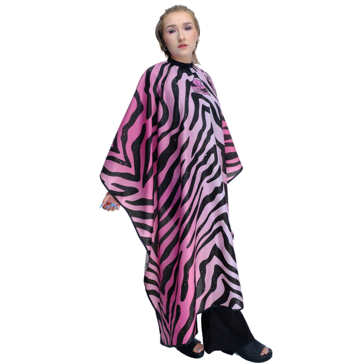 Person wearing a pink and black zebra hair stylist cape with a logo. 
Salon cape - hair stylist cape - zebra print hair stylist cape- pink hair stylist cape