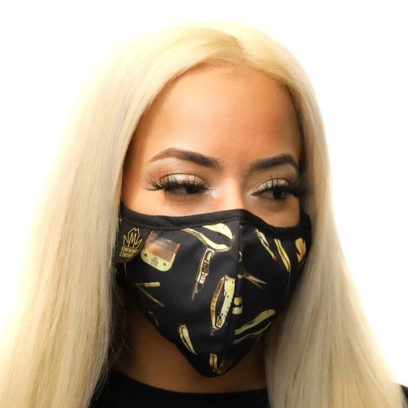 A person wearing a black face mask with a pattern that includes gold andMidas-themed designs.